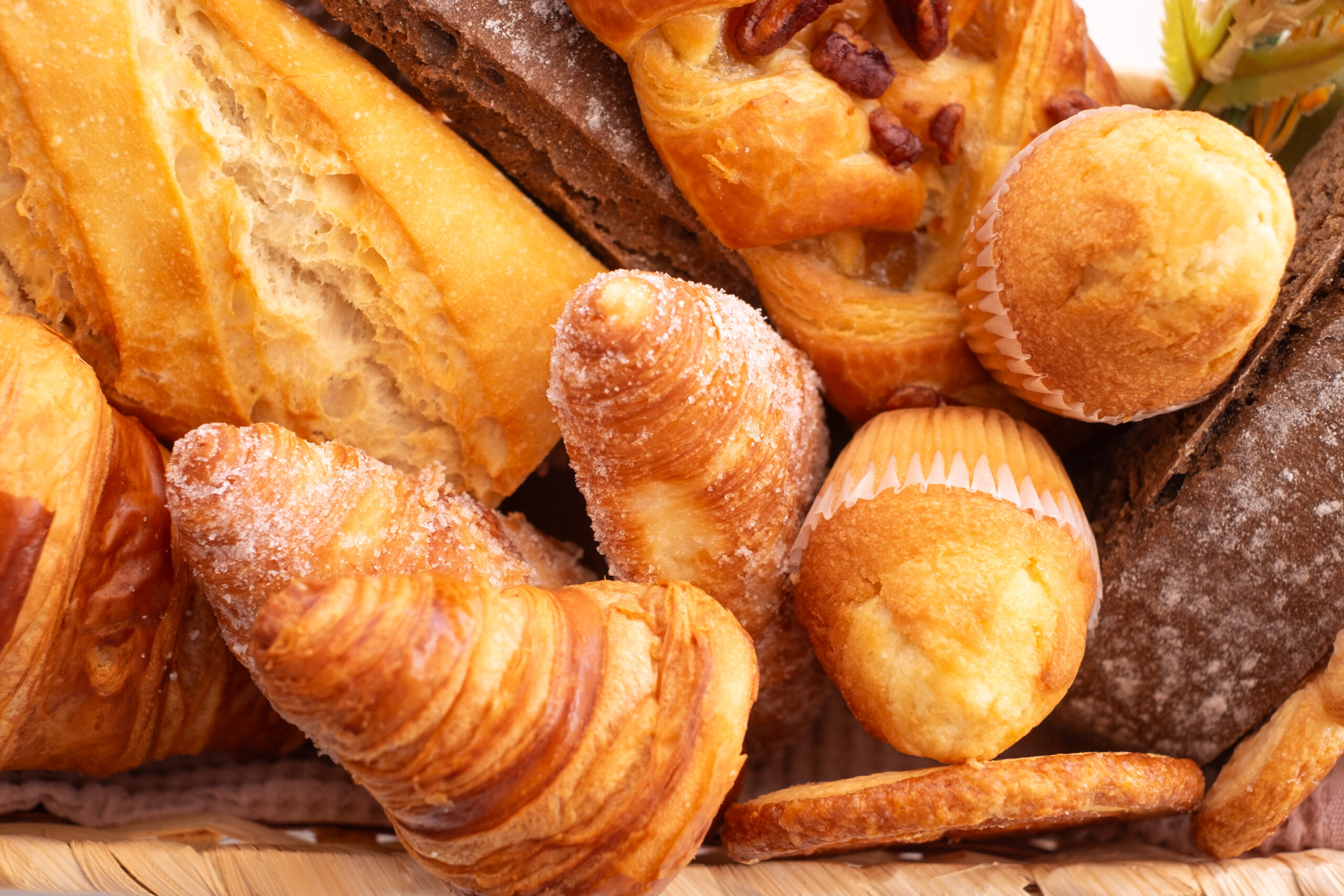 Close-up on bakery - various kinds of breadstuff. Rye bread, wholemeal, baguette, sweet bakery products and croissant captured from above (top view)
